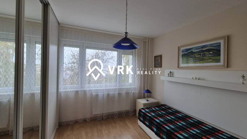 Szoba egy háromszobás lakásban fa dekorációjú padlóval és kék lámpával.