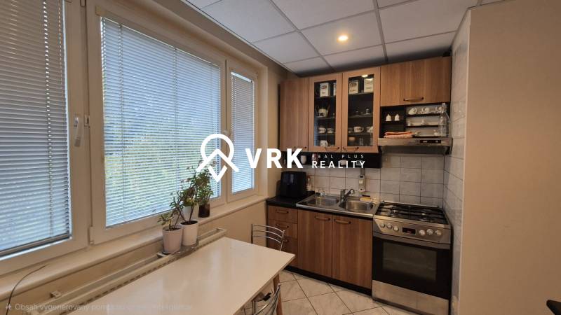 Konyha egy háromszobás lakásban gáztűzhellyel, szekrényekkel és étkezőasztallal.