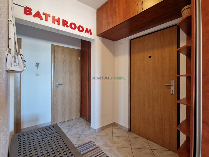 Előszoba egy háromszobás lakásban, ajtókkal és fogassal, padlón csempe.