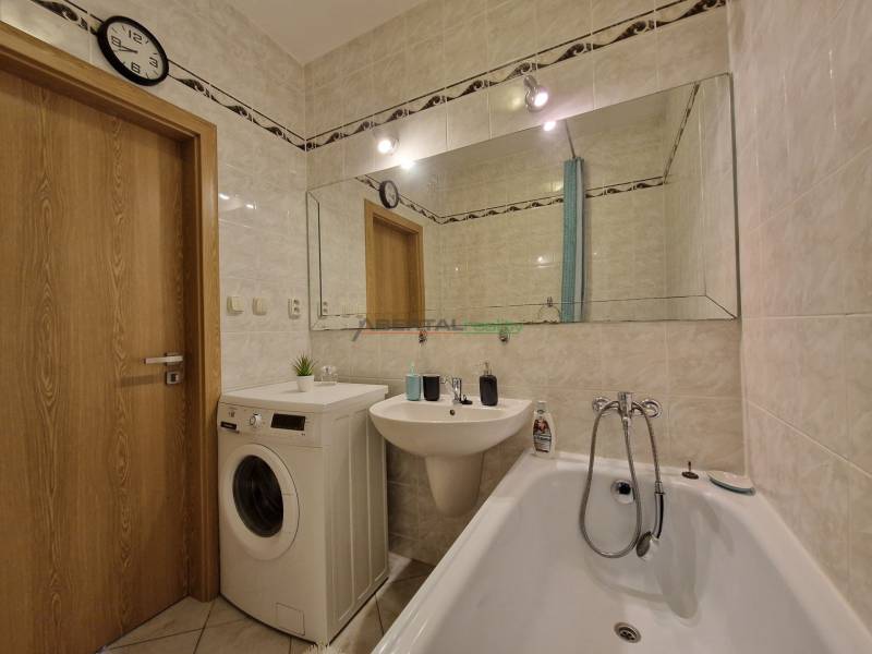 Fürdőszoba egy háromszobás lakásban káddal, mosógéppel és nagy tükörrel.