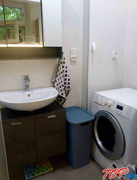 Fürdőszoba egy egyszobás lakásban tükörszekrénnyel, mosdóval és mosógéppel.