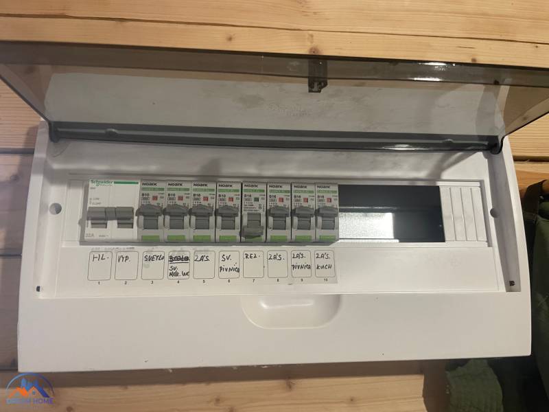 Elektromos elosztószekrény egy fahatású padlóval rendelkező házikóban.