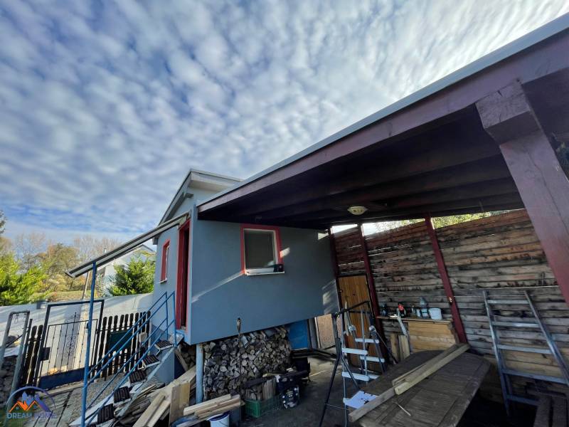 Ház Komáromban, az Újtelepen, lépcsővel és fa menedékkel a felhők alatt.