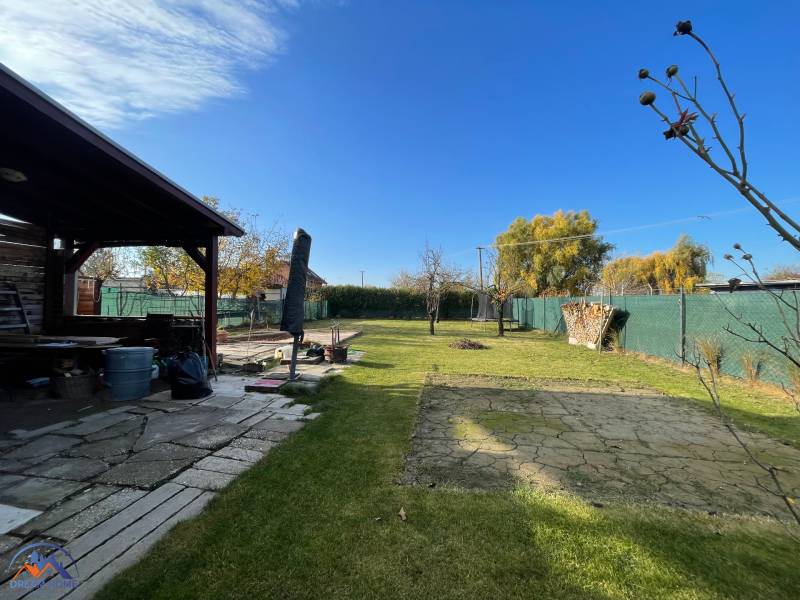 Kert a ház mellett az Új telep utcában, Komáromban, gyepes területtel és pavilonnal.