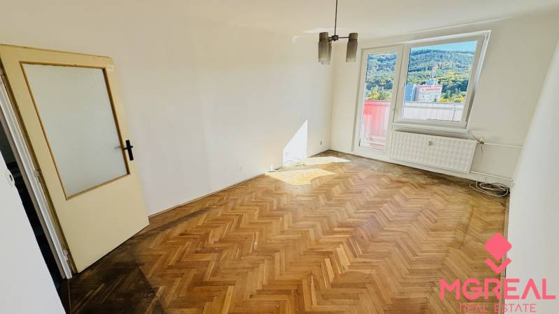 Szoba fa dekorációjú padlóval egy egyszobás lakásban, nagy ablak, üvegezett ajtó.