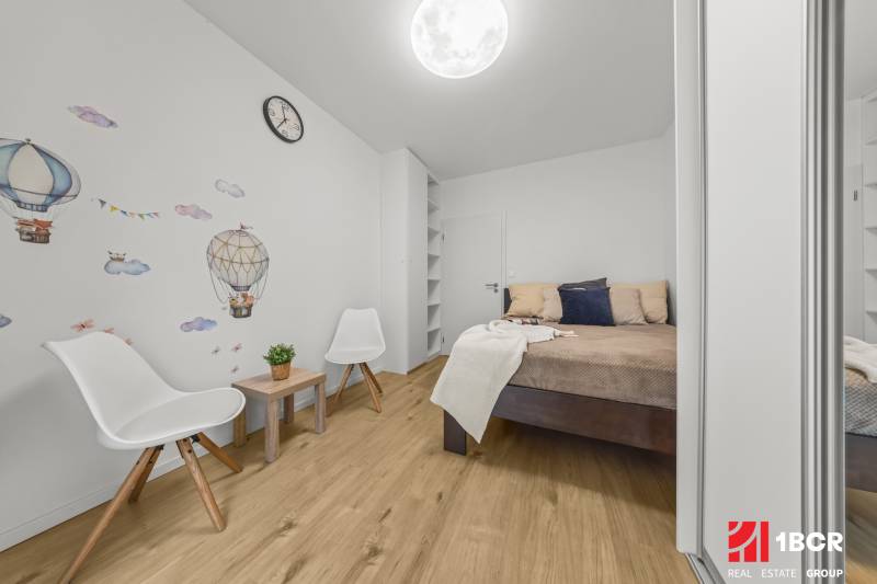 Hálószoba egy 2 szobás lakásban faldekorációval és fa dekorációjú padlóval.