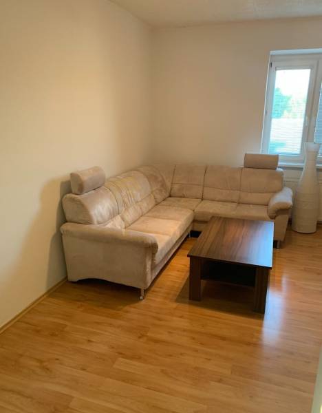 Nappali kényelmes kanapéval és dohányzóasztallal, fa dekorációjú padlón.