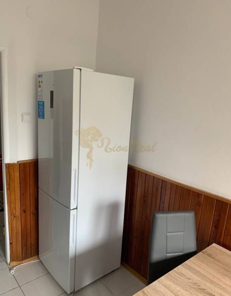 Konyha egy kétszobás lakásban hűtőszekrénnyel, sötét burkolattal és étkezősarokkal.