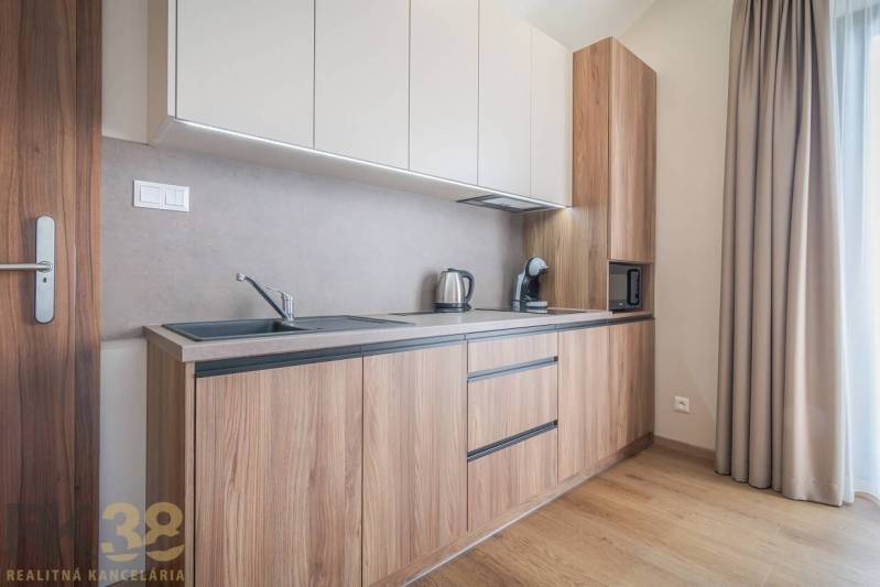 Konyha egy kétszobás lakásban, fa dekorációjú padlóval és világos konyhabútorral.