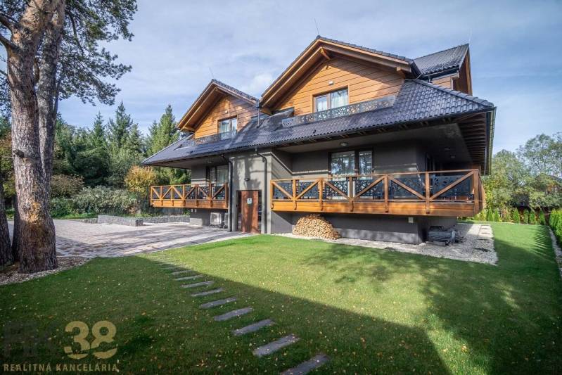 Kétszintes ház fa elemekkel és zöld gyep Tatranská Lomnicában.