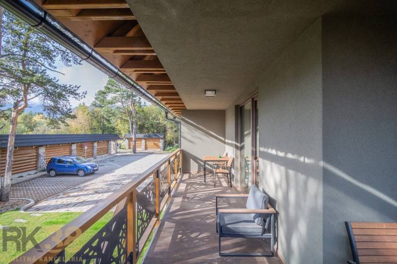 Tatranská Lomnica 2 szobás lakásának erkélye fa dekorációval és kültéri ülőgarnitúrával.