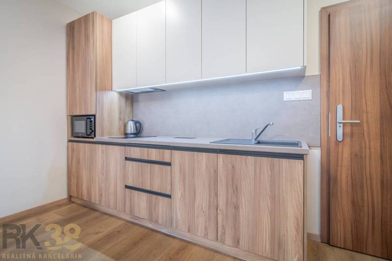 Konyhaszekrény fa dekorral, beépített készülékek és fa dekor padló egy 2 szobás lakásban.