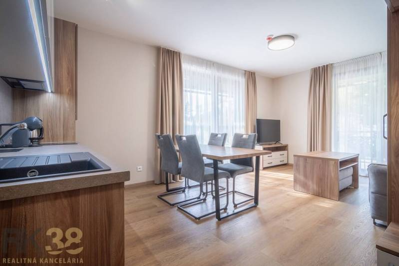 Tágas belső tér egy kétszobás lakásban fa dekorációjú padlóval és étkezőasztallal.