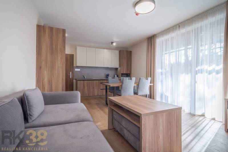 Nappali egy kétszobás lakásban, fa dekorációjú bútorokkal és padlóval.