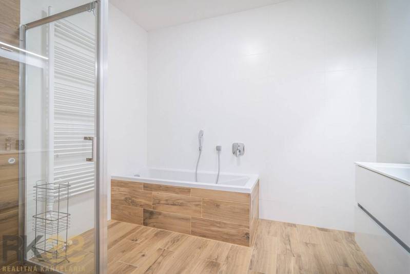 Fürdőszoba káddal és fa dekorációjú padlóval egy kétszobás lakásban.