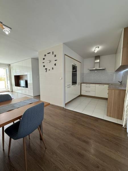 Étkező tér egy 4 szobás lakásban fa mintázatú padlóval és háttérben a konyhával.