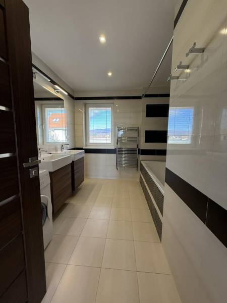 Fürdőszoba egy négy szobás lakásban káddal, mosdókkal és mosógéppel.