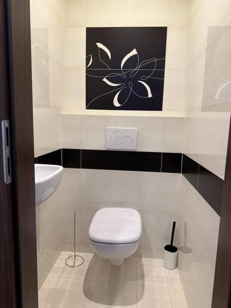 Fürdőszoba függesztett WC-vel és mosdóval egy 4 szobás lakásban, virágmintával díszítve.