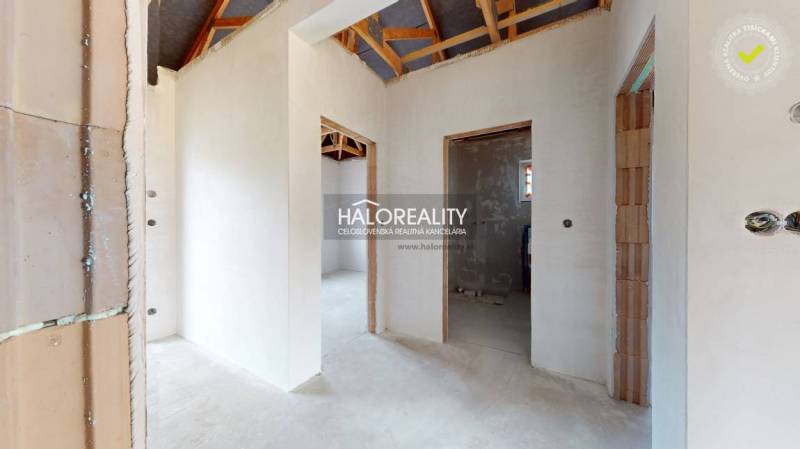 Családi ház belső tere vakolatlan falakkal és látható tetőszerkezettel.