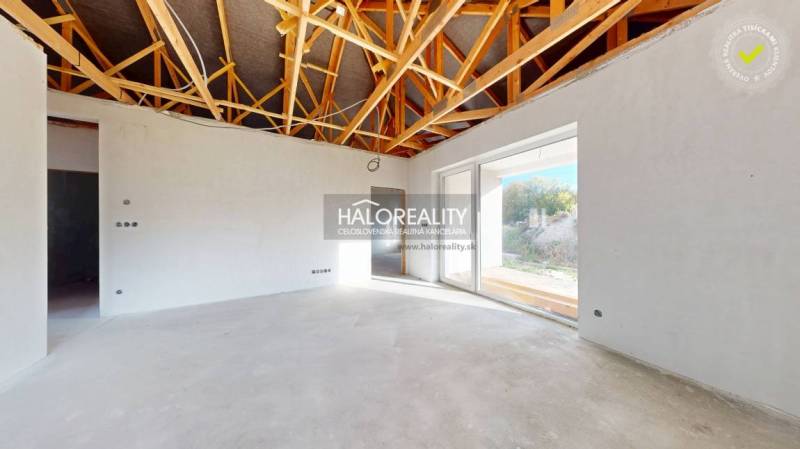 Családi ház belső tere feltárt mennyezettel és nagy üvegezett ajtókkal.