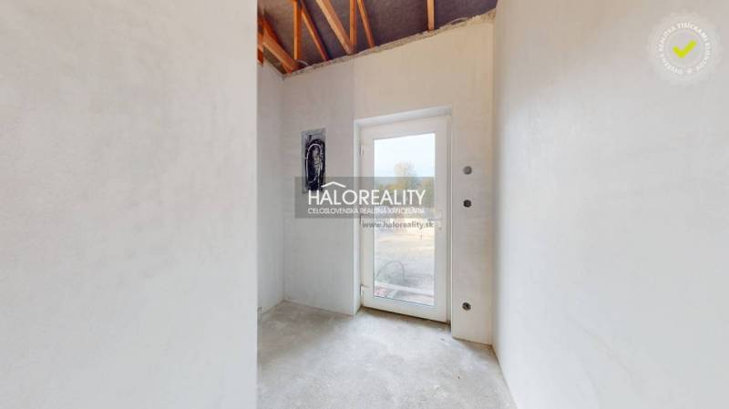 Világos szoba egy családi házban betonpadlóval és üvegajtókkal.