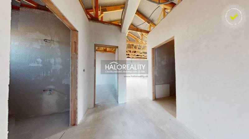 Családi ház befejezetlen belső tere fa tetőszerkezettel és nyitott helyiségekkel.