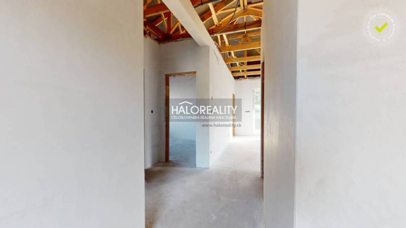 Családi ház belső tere tetőszerkezettel és fehér vakolt falakkal.