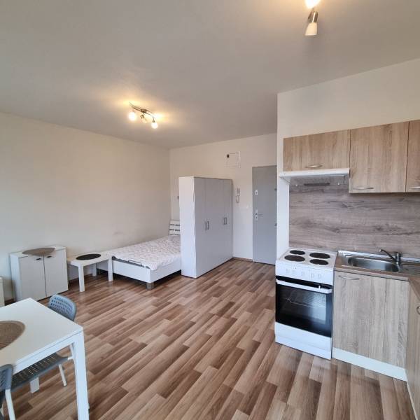 Garzonlakás konyhasarokkal, székkel és fa dekorációjú padlóval.