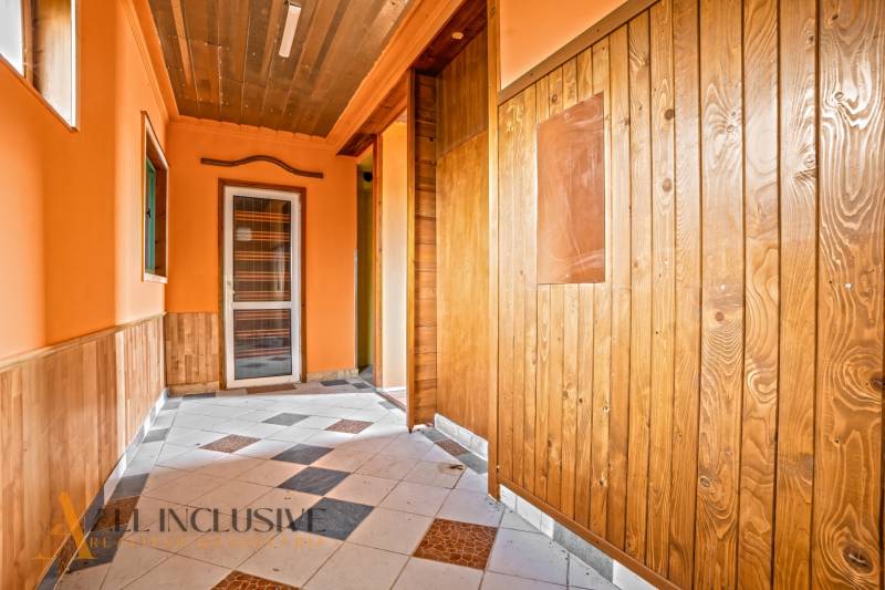 Egy családi ház folyosója fa burkolattal és csempézett padlóval.