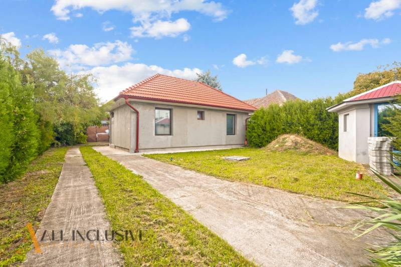 Családi ház Bátorkeszin, gyepes udvarral, beton járdával és piros tetővel.