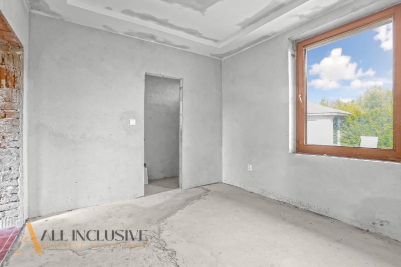 Családi ház belső tere befejezetlen falakkal és nagy ablakkal.