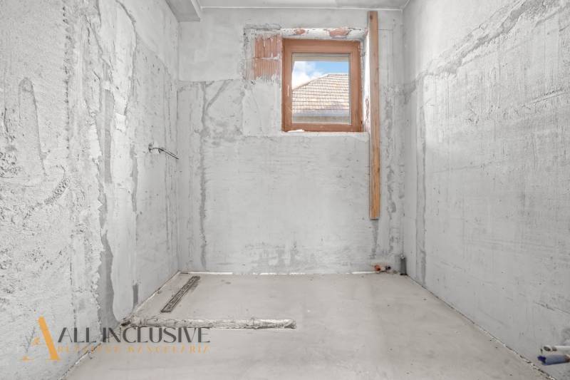 Fürdőszoba felújítása családi házban, vakolatlan betonfalak, egyetlen kis ablak.