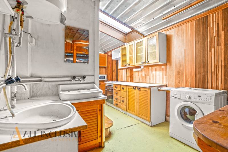 Konyha egy családi házban fa szekrényekkel, mosogatóval és mosógéppel.