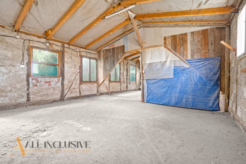 Családi ház belső tere nyers falakkal és fa gerendákkal.