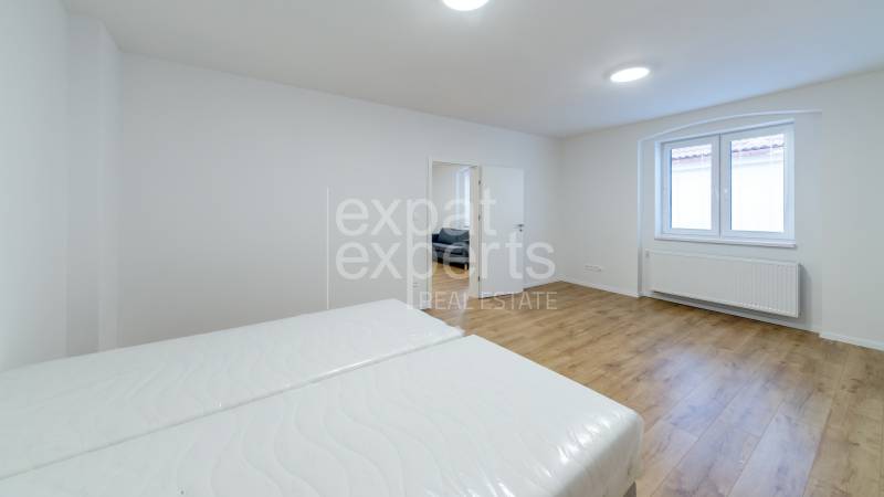 Hálószoba egy háromszobás lakásban, fa dekor padlóval és fehér falakkal.