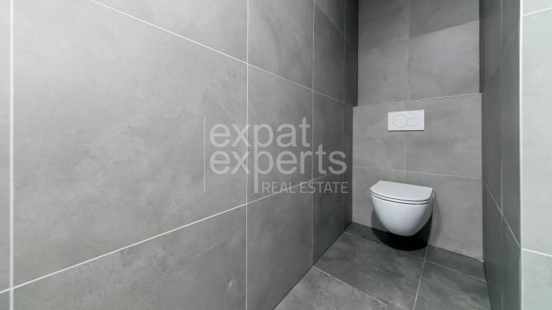 Fürdőszoba egy háromszobás lakásban kerámia burkolatokkal és függesztett WC-vel.