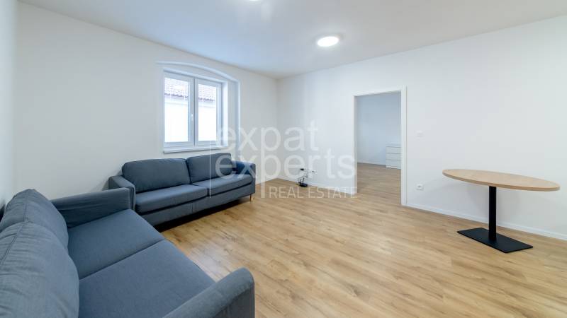 Nappali kék kanapékkal és fa dekorációjú padlón lévő asztallal.