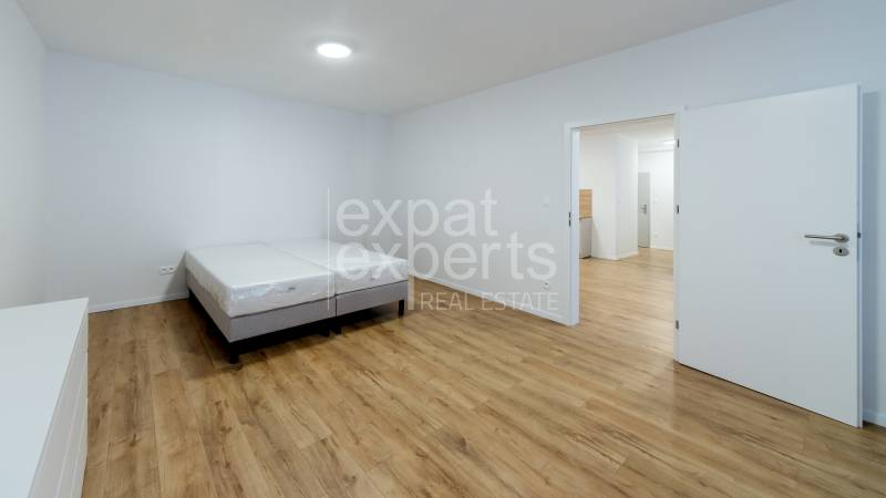 Hálószoba egy háromszobás lakásban, ággyal és fa dekorációjú padlóval.