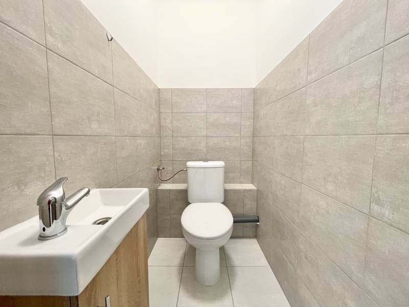 Iroda szürke csempékkel és mosdóval ellátott mosdója.