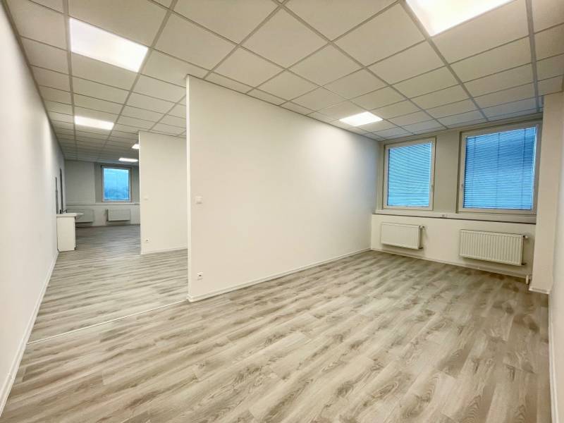 Irodák fehér mennyezettel és fa dekorációjú padlóval, két nagy ablakkal.