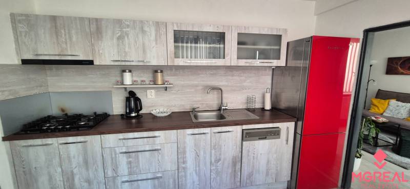 Konyha egy kétszobás lakásban, piros hűtőszekrénnyel és fa dekorációjú padlóval.