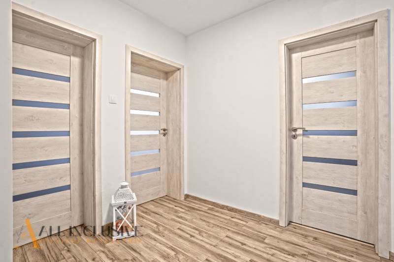 Családi ház belső tere fa dekorációjú padlóval és fehér ajtókkal.