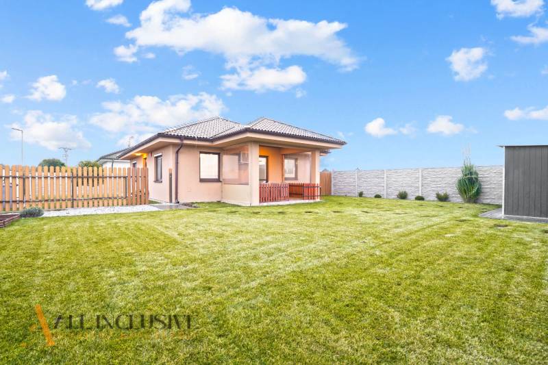 Családi ház Nagymagyaron nagy kerttel, gyepfelülettel és kerítéssel.