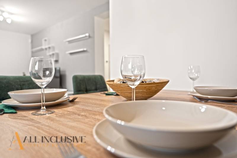 Étkezőasztal poharakkal, tányérokkal és tálkával egy családi ház belső terében.