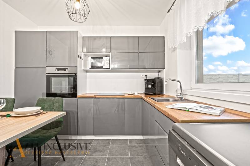 Konyha szürke konyhabútorral, beépített sütővel és mikrohullámú sütővel egy családi házban.