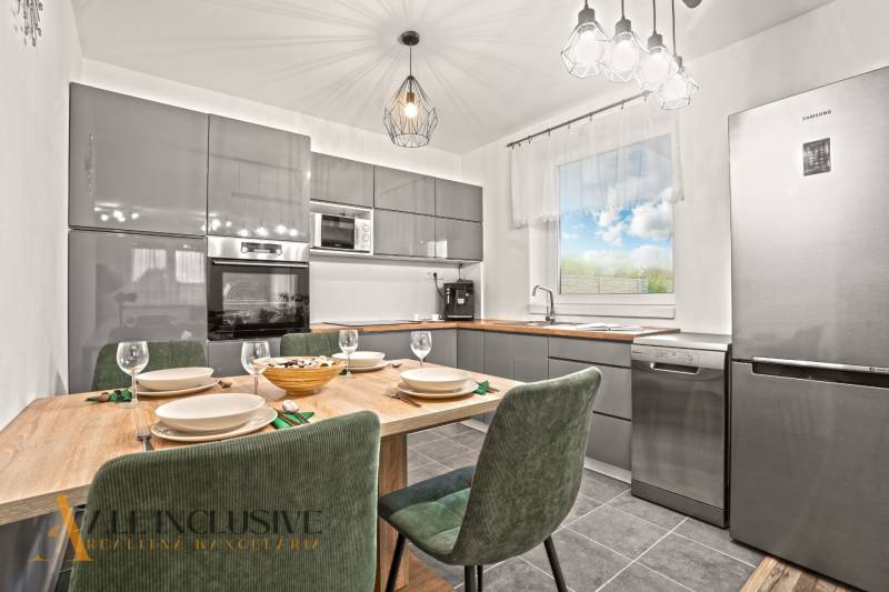 Modern konyha családi házban fa dekorációjú asztallal és több háztartási géppel.