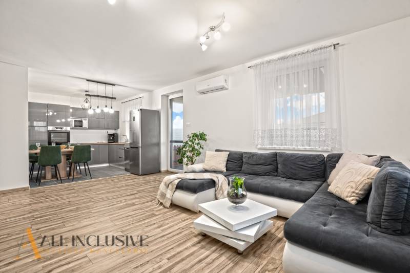 Nappali konyhával, fa mintázatú padlóval, összekapcsolt tér egy családi házban.