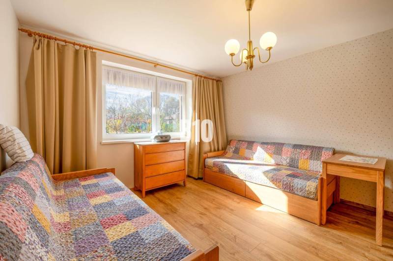 Szoba családi házban ágyakkal, fa dekorációval és színes takarókkal.