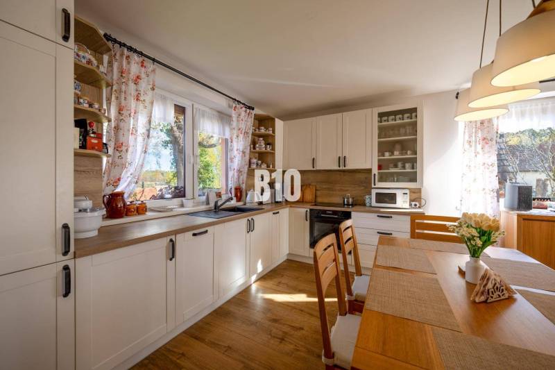 Konyha egy családi házban, fa dekoros padlóval és világos bútorokkal.