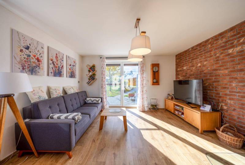 Nappali családi házban kanapéval, téglafallal és fa dekorációjú padlóval.